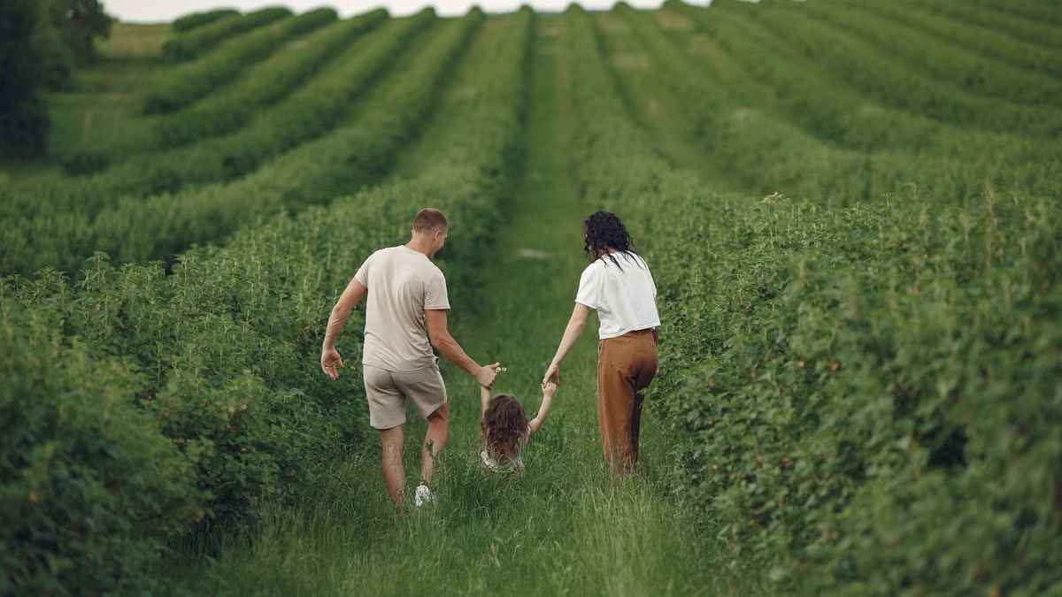 Happy family walking together through a lush green field enjoying nature and togetherness.